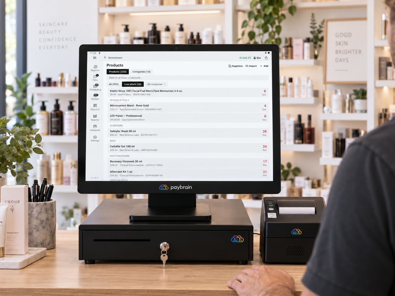 At a skincare shop counter, the register's Products screen filtered to low stock, each item showing its count against its threshold